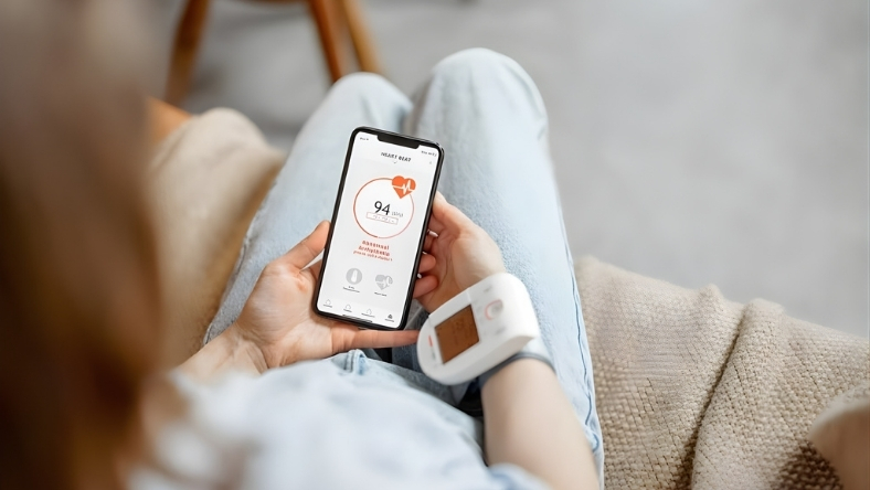 Person checking heart rate on smartphone with wrist monitor