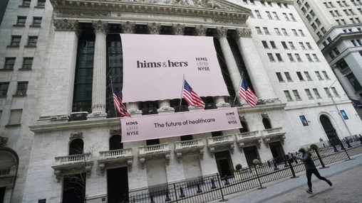 Hims and Hers IPO banner on the New York Stock Exchange with American flags and a pedestrian in the foreground
